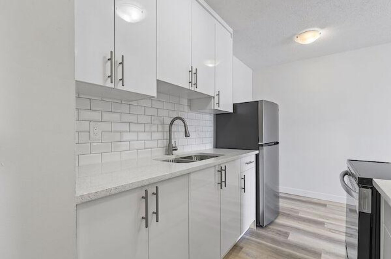 Clean apartment kitchen with white cabinets, subway tile and stainless steel appliances