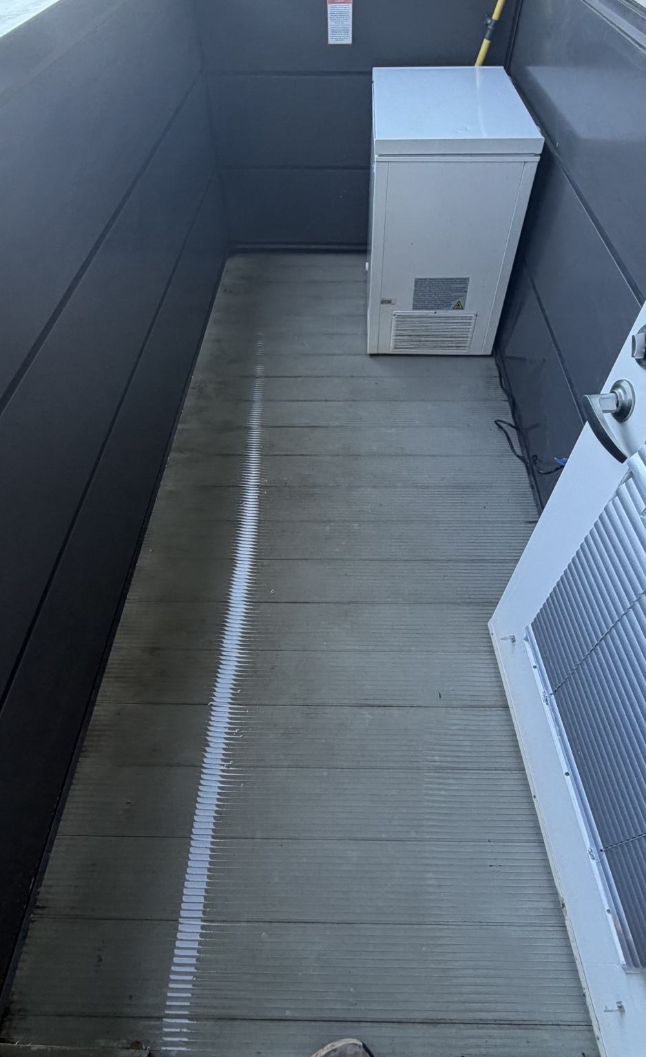 The same upper-floor student housing patio after cleaning, with cleaner decking still wet from the work