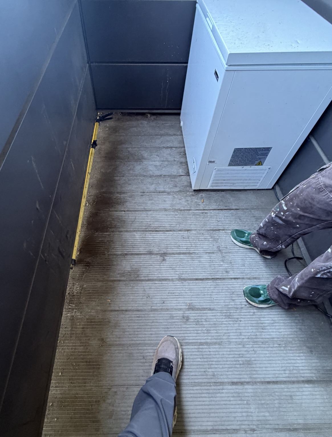 Upper-floor student housing patio with dirt and debris along the decking and wall edges before cleaning